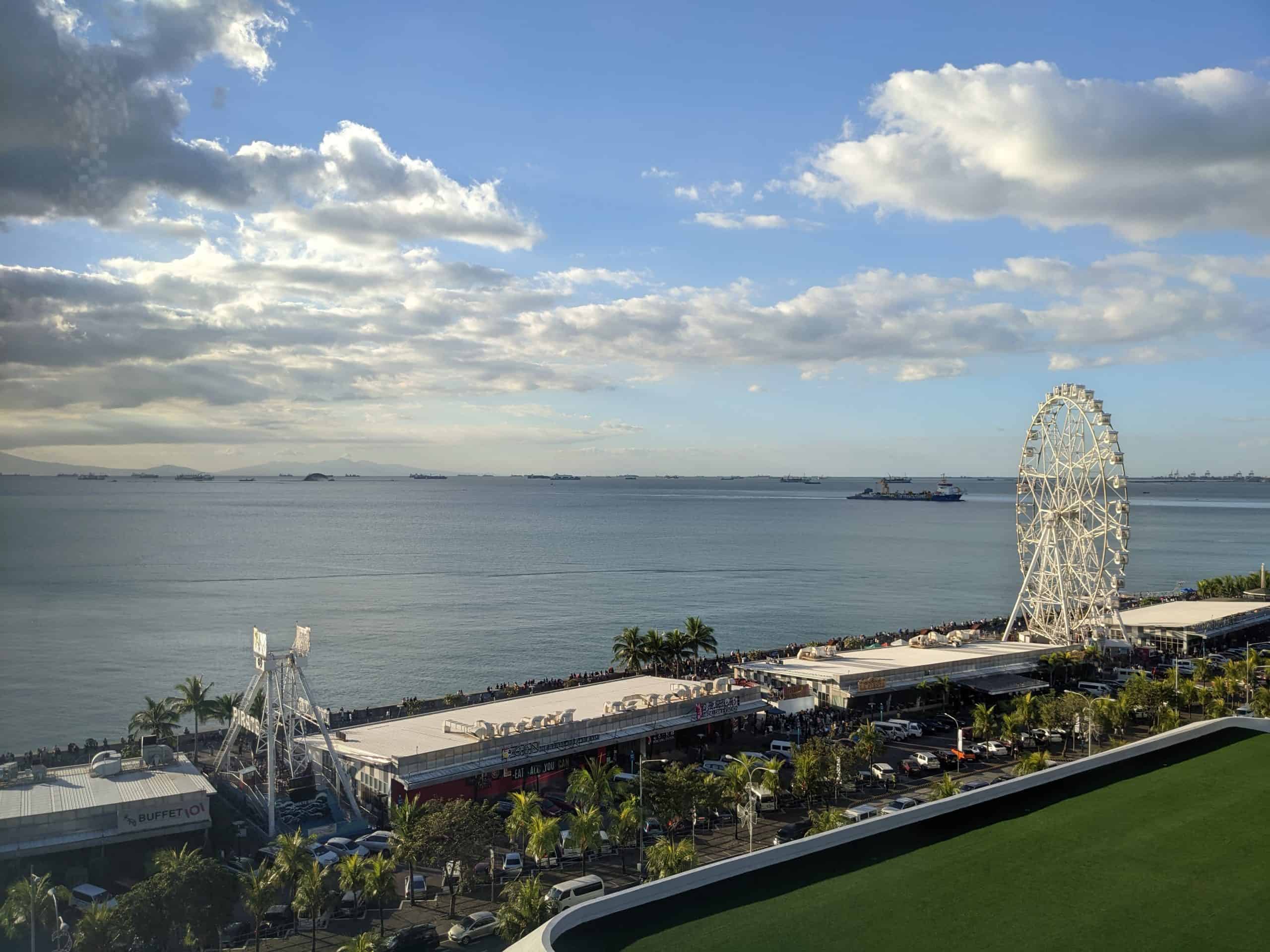 Daytime view of Manila Bay, the boardwalk, and a Ferris wheel